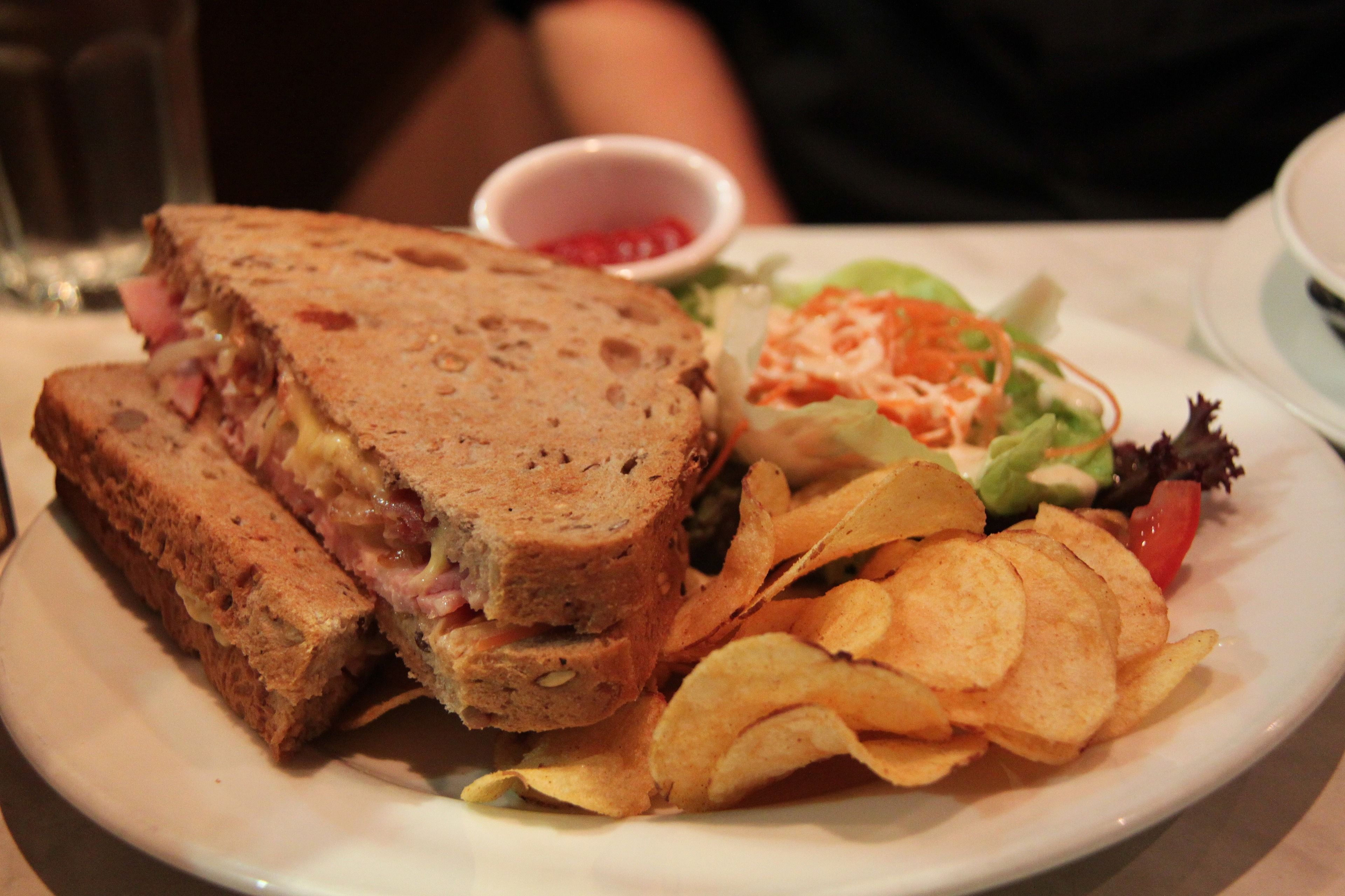 A plate with a sandwich, salad, and chips.
