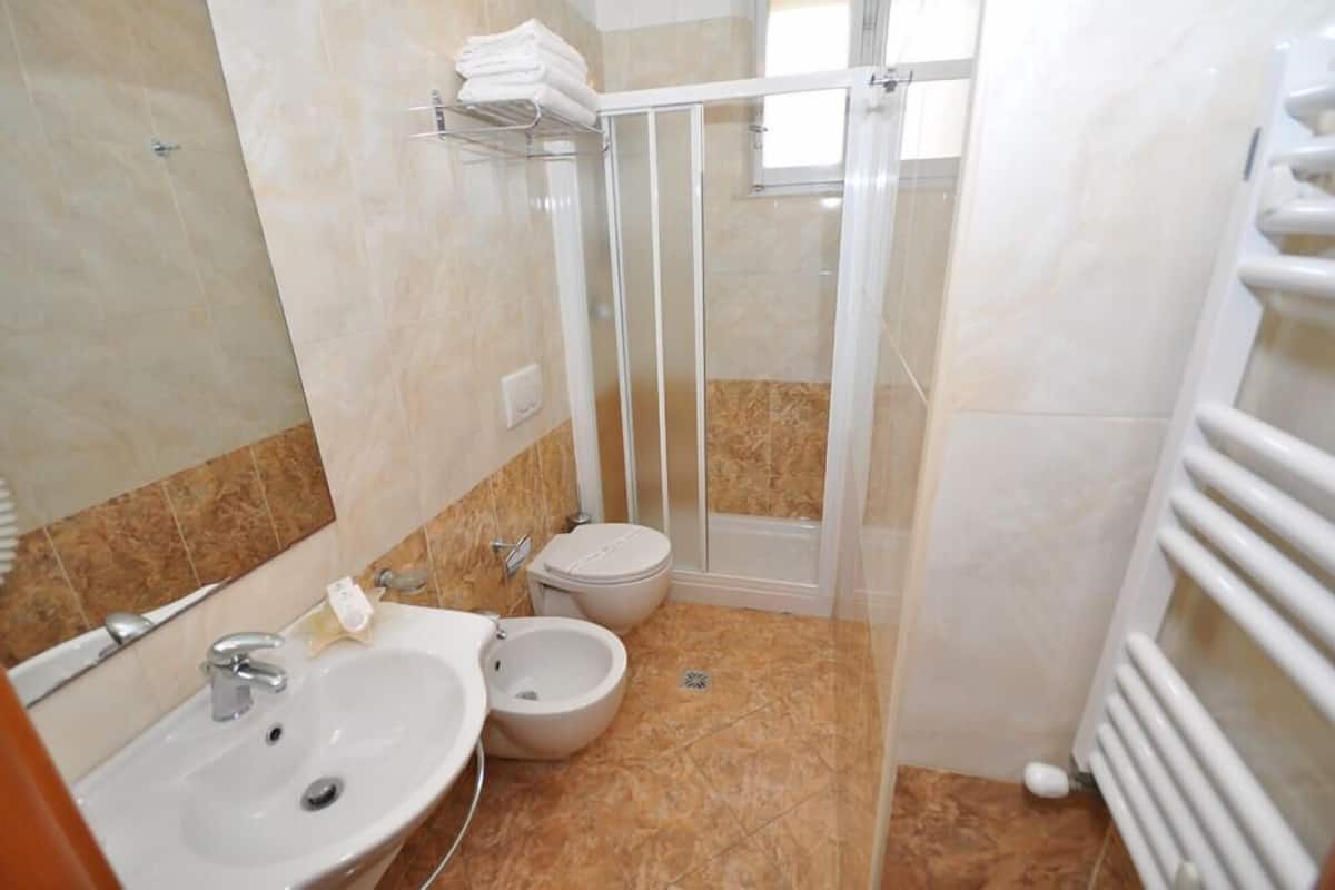 A bathroom with a sink, bidet, toilet, and glass-enclosed shower.
