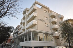 Et moderne hotel med en beige facade, flere balkoner og store vinduer.