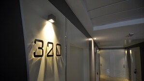 Un couloir avec le numéro « 320 » illuminé sur le mur, qui mène à une porte.