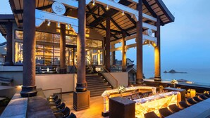 A covered outdoor area with a bar and seating, large columns, and a view of the sea. - Angsana Zhuhai Phoenix Bay (Zhuhai)