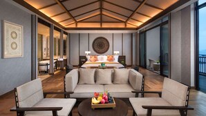 A modern hotel room with a large bed, two sofas, a coffee table with fruit, and a view of the sea. - Angsana Zhuhai Phoenix Bay (Zhuhai)