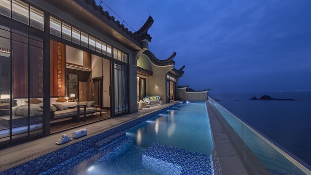 A modern hotel with a traditional architectural style, featuring a large infinity pool and a view of the sea. - Angsana Zhuhai Phoenix Bay (Zhuhai)