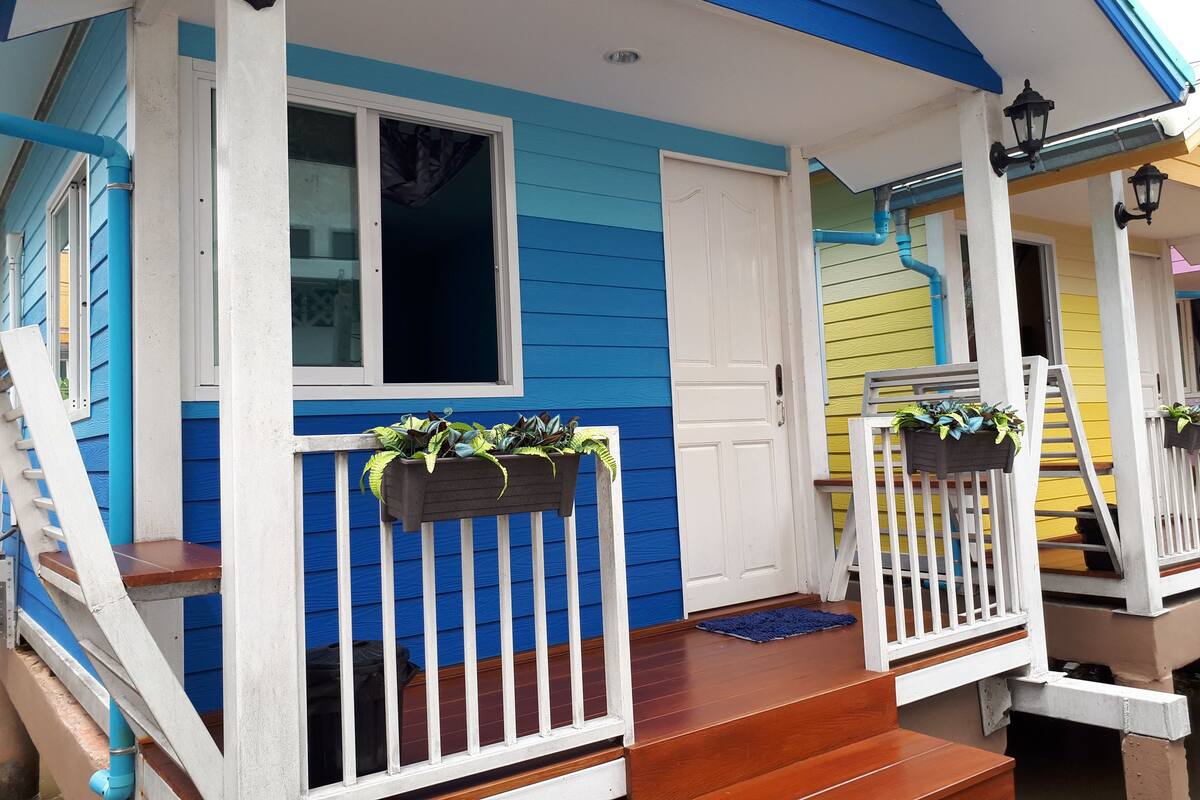Una casa azul y blanca con un porche, una puerta blanca y una ventana.