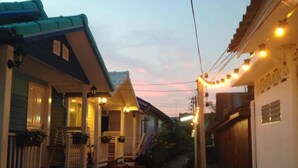 A row of houses with front porches, some with steps leading up to them, and string lights along the street. - Se Sun Amphawa (Amphawa)