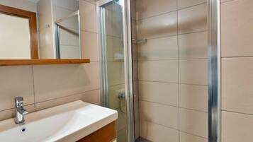 Un baño con lavamanos blanco, espejo y cabina de ducha de vidrio.
