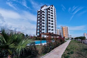 A high-rise residential building with a swimming pool and a covered walkway. - Upart Home (Mersin)