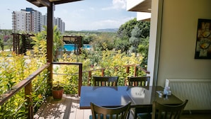 A balcony with a table and chairs, overlooking a swimming pool and lush greenery. - Upart Home (Mersin)