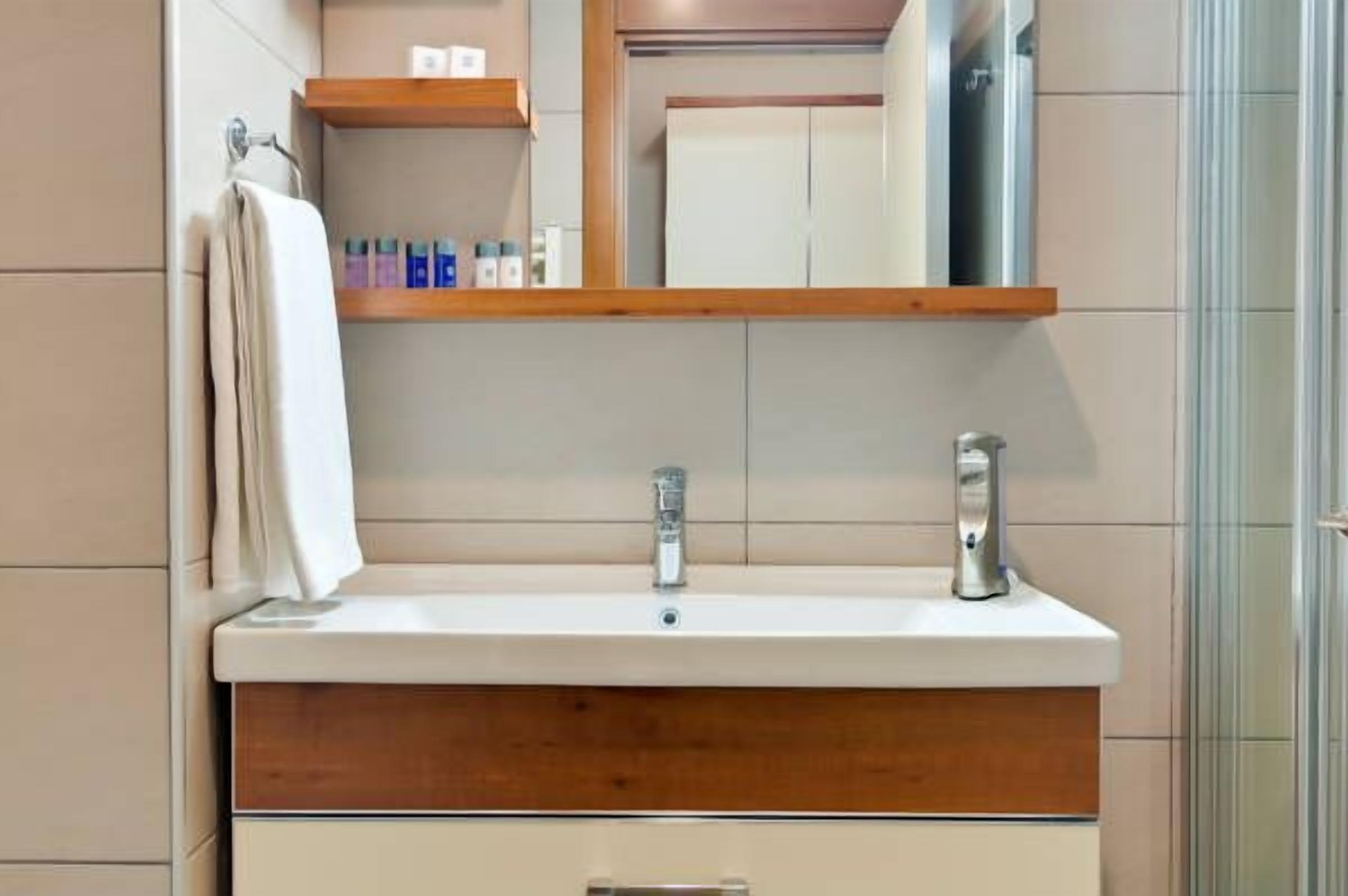 Une salle de bain avec un lavabo blanc, un meuble-lavabo en bois et un miroir au-dessus du lavabo.