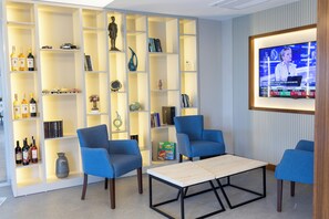 A modern living room with a TV, blue chairs, a coffee table, and a bookshelf with various items. - Upart Home (Mersin)