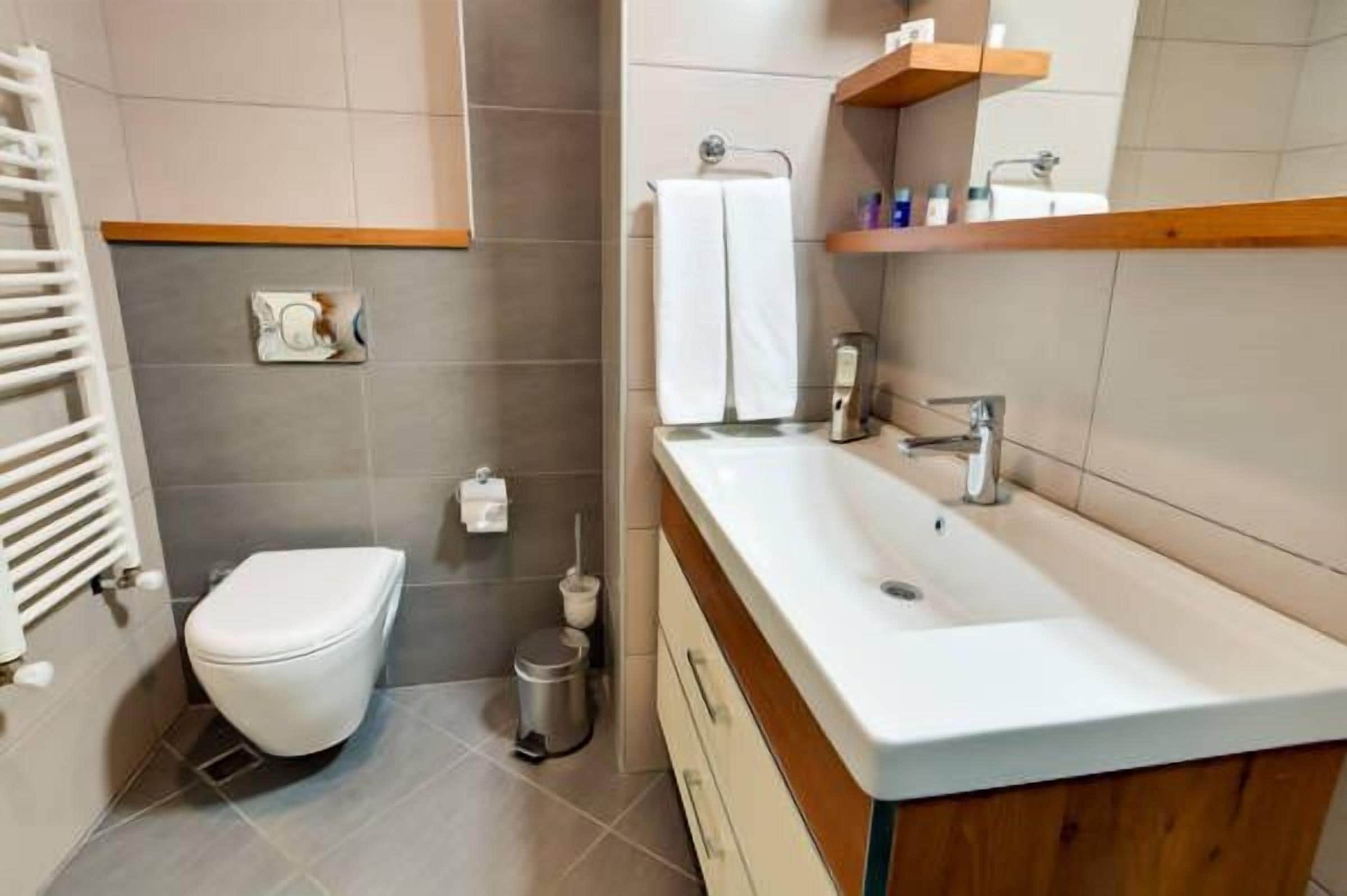 A modern bathroom with a white toilet, a sink with a wooden countertop, and a towel rack.
