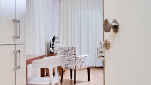 A hotel room with a wooden dining table, white chairs, and a patterned tablecloth. - Upart Home (Mersin)