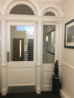 A hallway with a white door, a glass door, and a staircase. - Apple Apartments Devanha Gardens (Aberdeen)