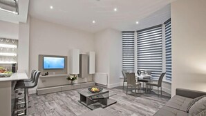 Un salon moderne comprenant un canapé, une table basse, un téléviseur et un coin repas avec des chaises et une table.