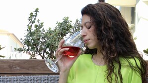 A person sitting on a wicker bench outdoors, holding a glass. - Hotel Adigrat (Riccione)