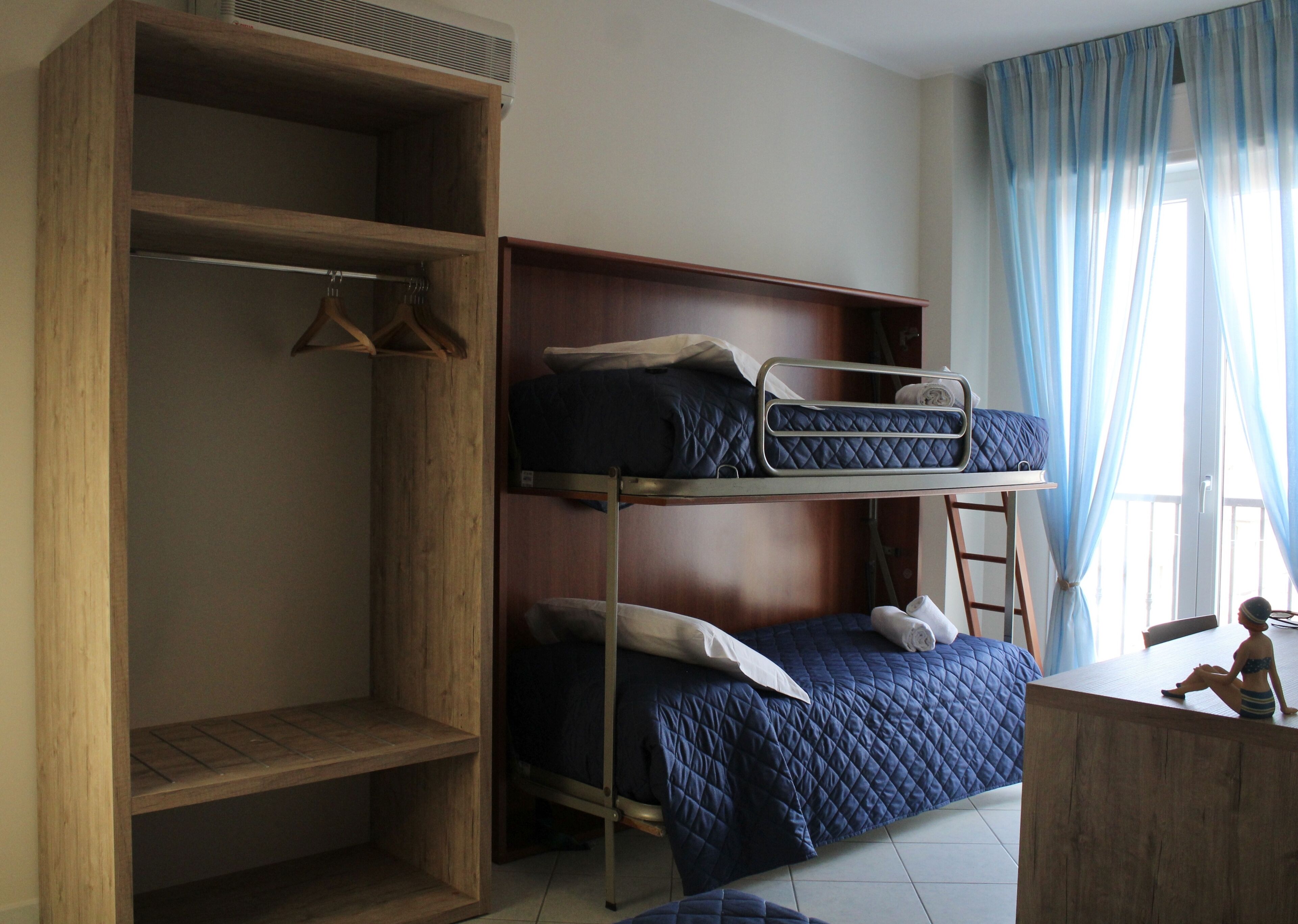 Un dormitorio con literas, un armario de madera y un escritorio.