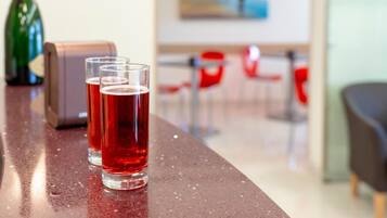 A bar area with glasses of red beverage, a bottle, and a cash register.