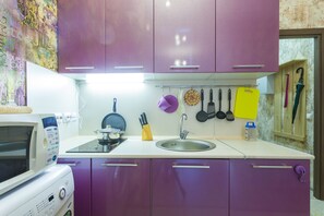 Compact kitchen area with microwave, stainless steel sink, and organized utensils.