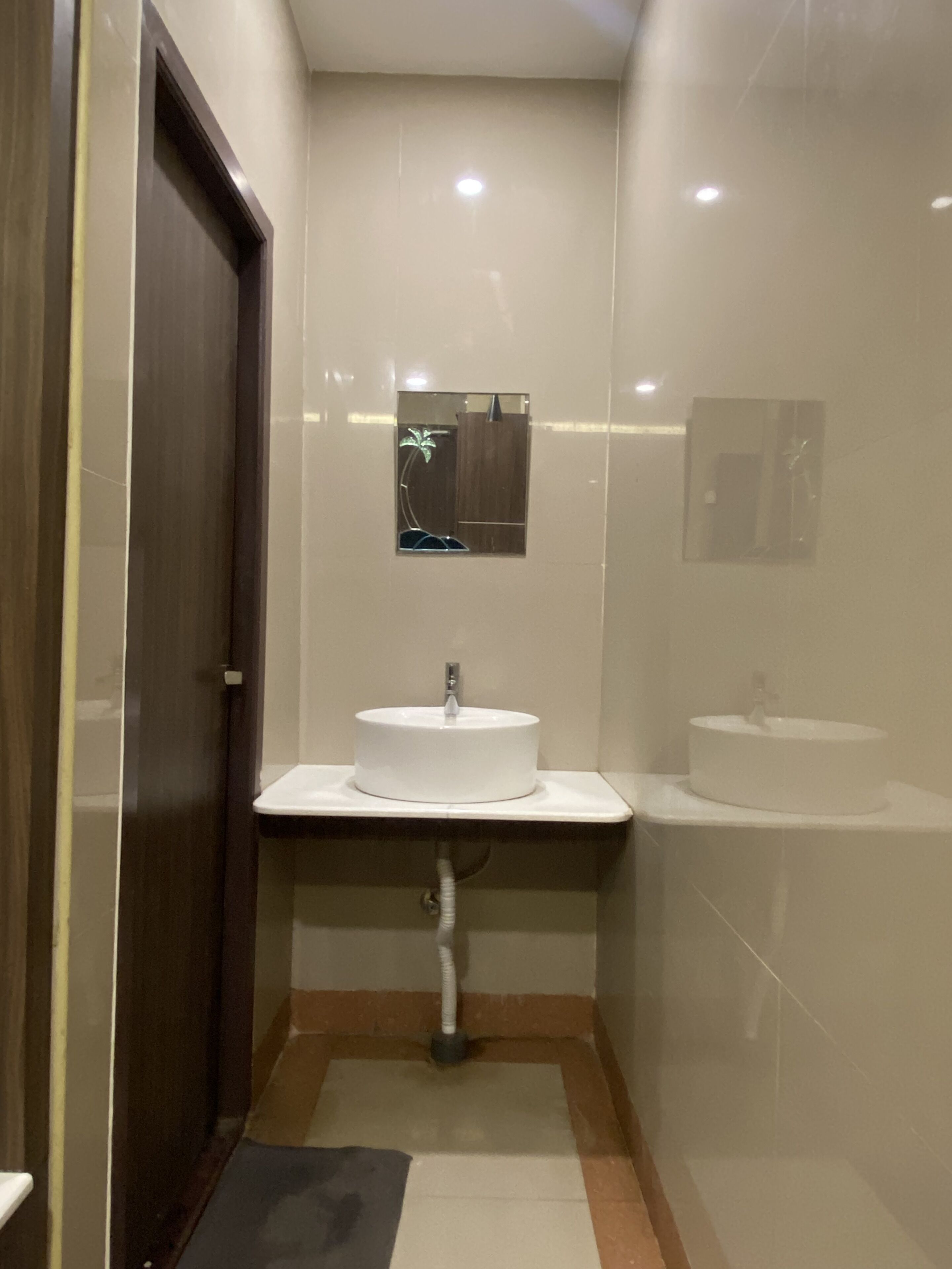 A bathroom with a white sink, a mirror above it, and a door to the left.