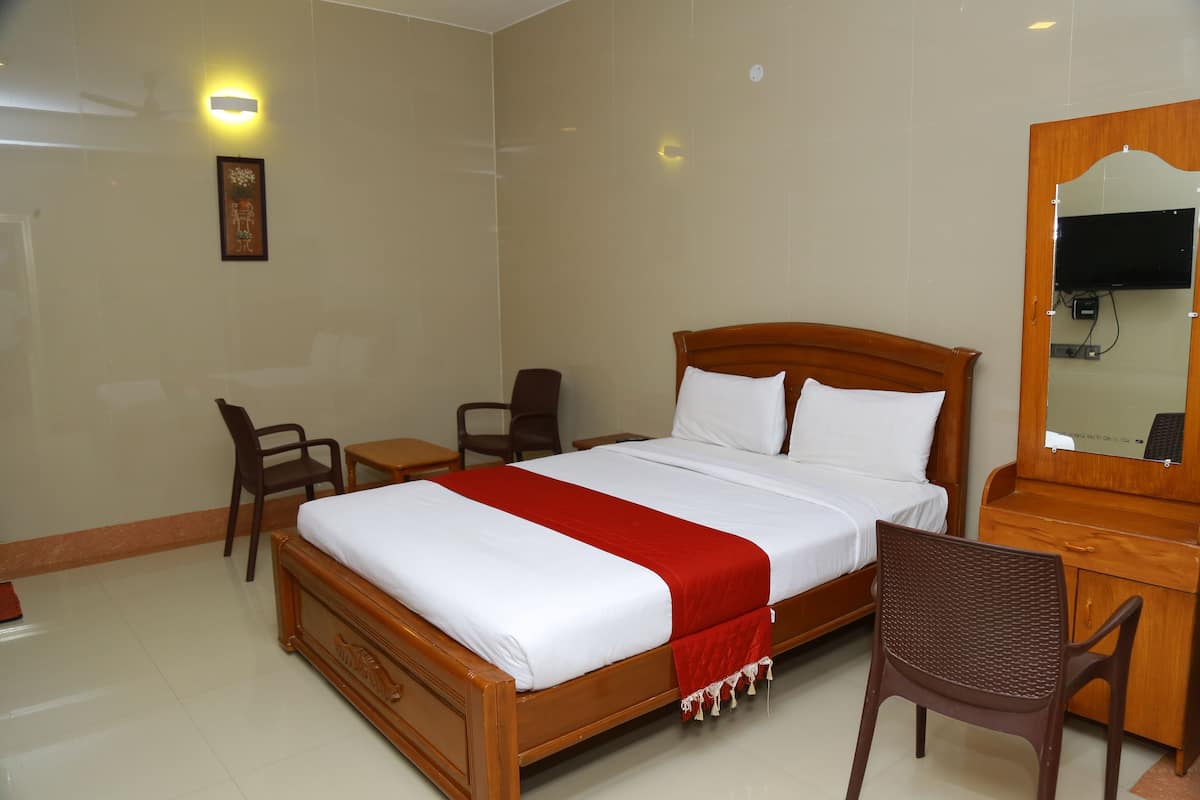 A hotel room with a wooden bed, a desk, a chair, a mirror, and a wall-mounted light fixture.
