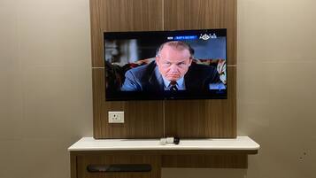 Un televisore fissato a una parete di legno, con un telecomando e una presa di corrente sotto.