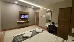 Une chambre d’hôtel moderne équipée d’un lit, d’un téléviseur fixé au mur, d’un bureau, d’une chaise et d’une armoire.