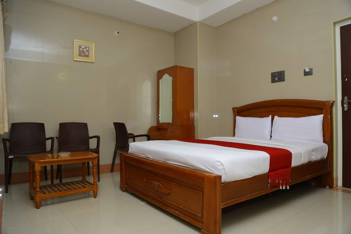 A hotel room with a wooden bed, a small wooden table, two chairs, a mirror, and a picture on the wall.