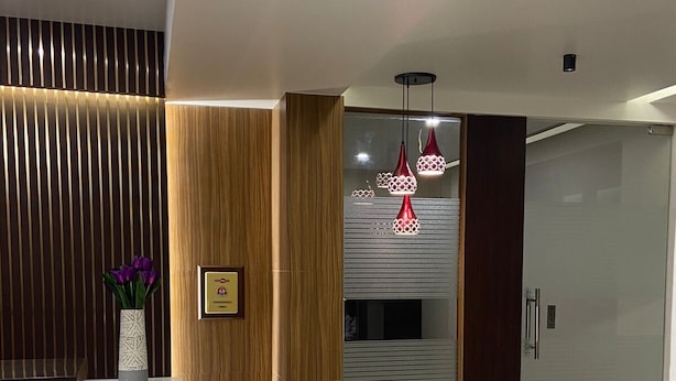 Un espace d’accueil au design moderne, comprenant un comptoir de réception, une statue de Bouddha et une plante en pot.