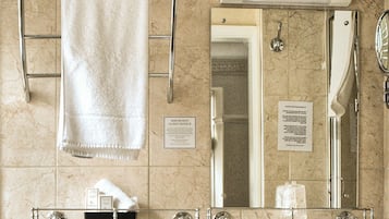 Une salle de bain avec un mur en marbre, un porte-serviettes, un lavabo et un miroir.