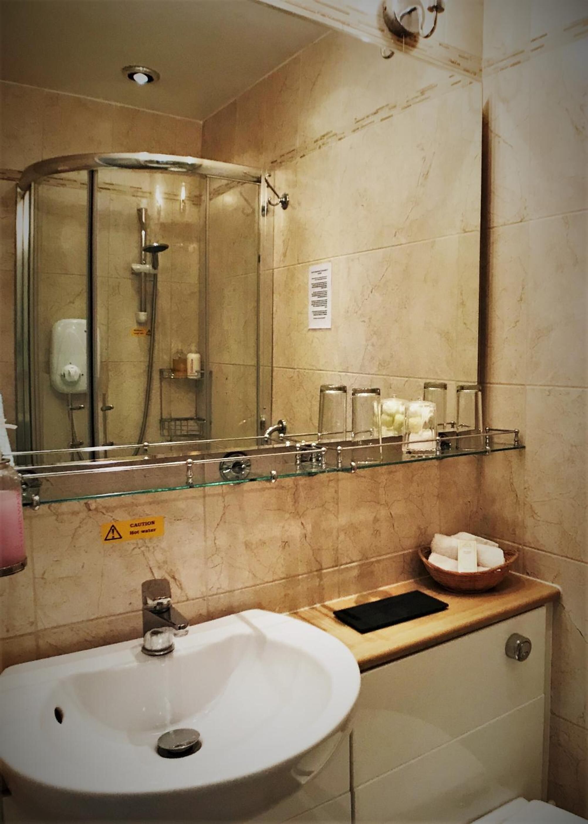 A bathroom with a glass shower enclosure, a sink, and a mirror.
