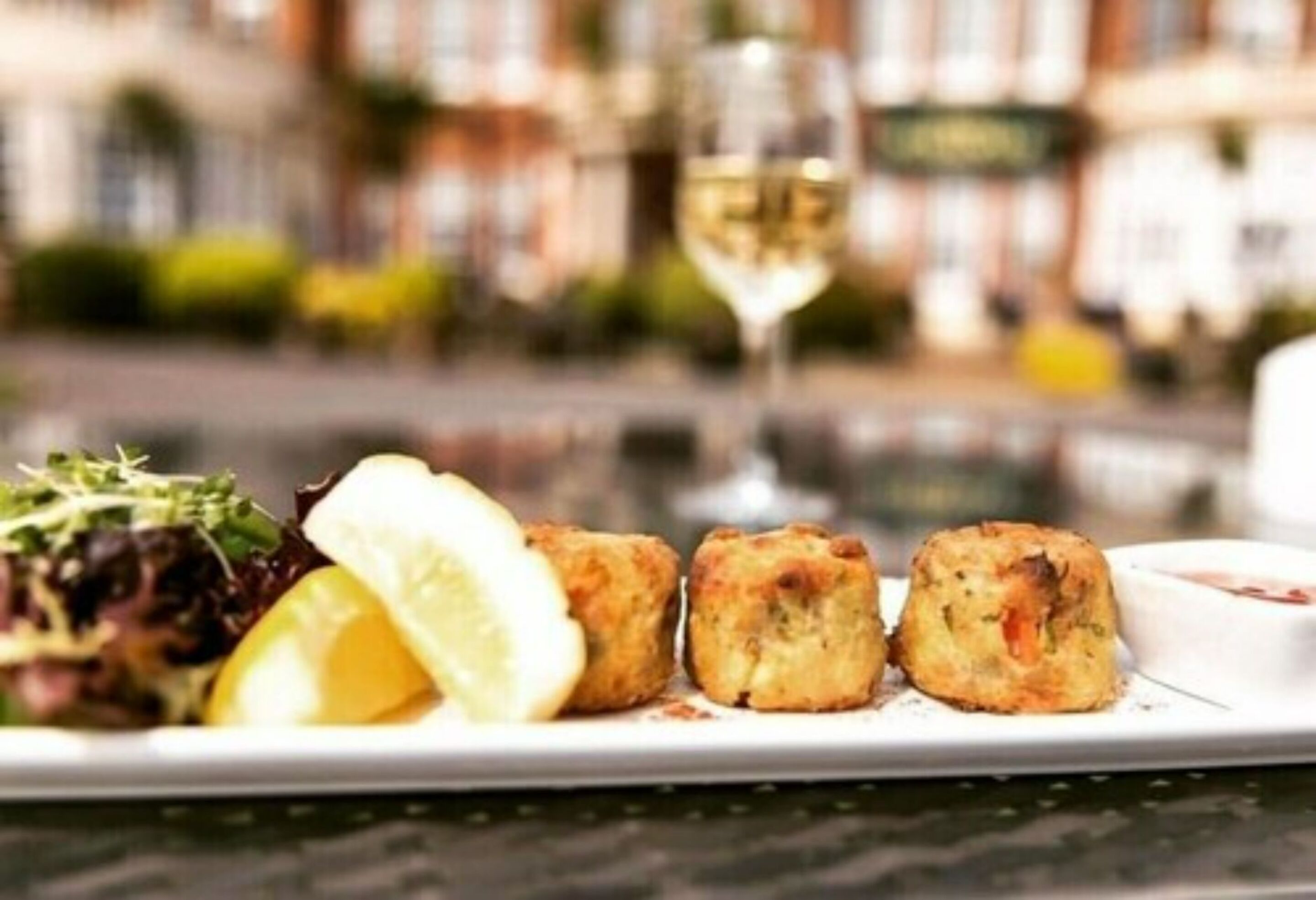 A plate with food and a glass of white wine.