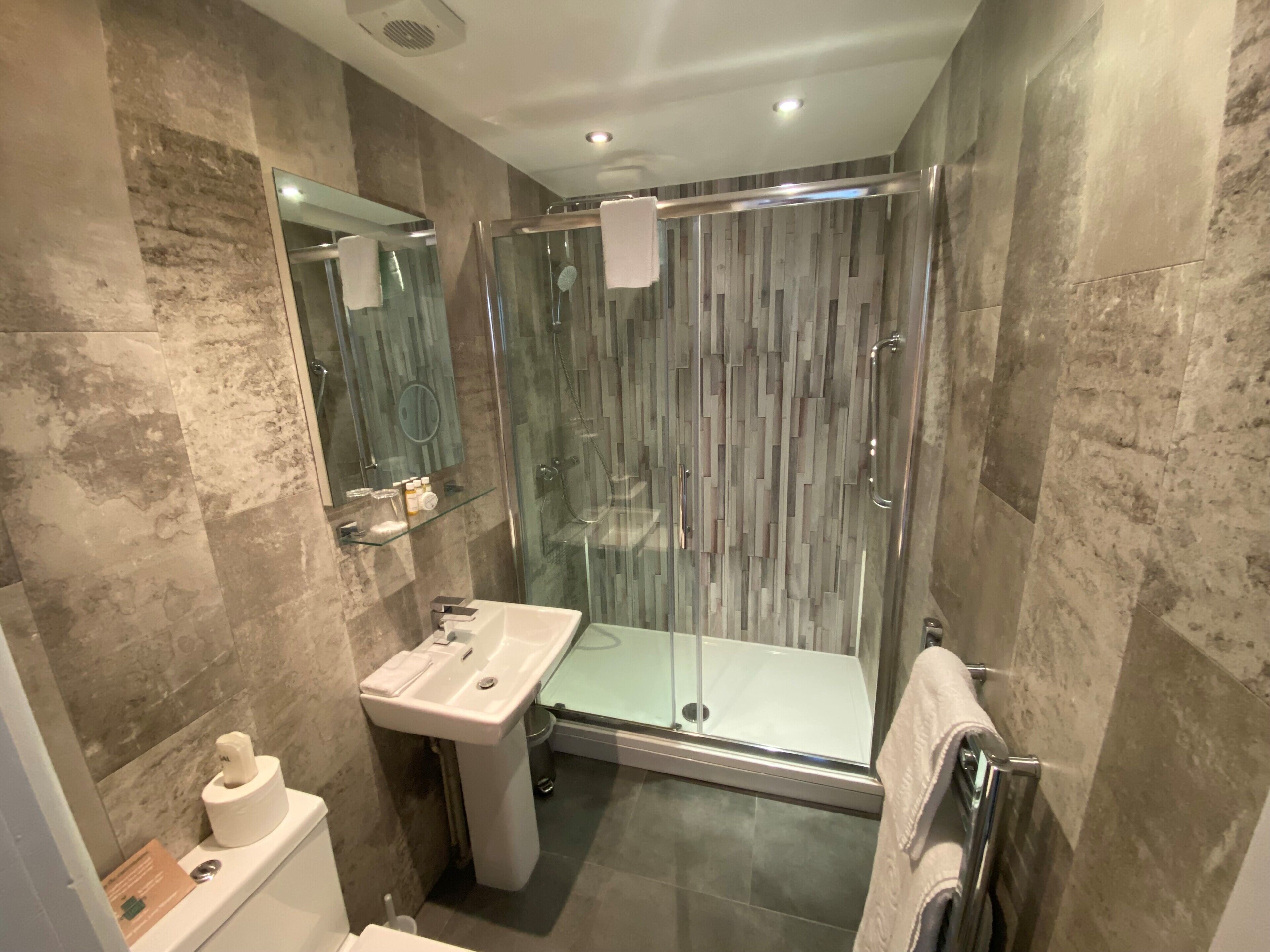A modern bathroom with a glass-enclosed shower, a sink with a mirror, and a toilet.