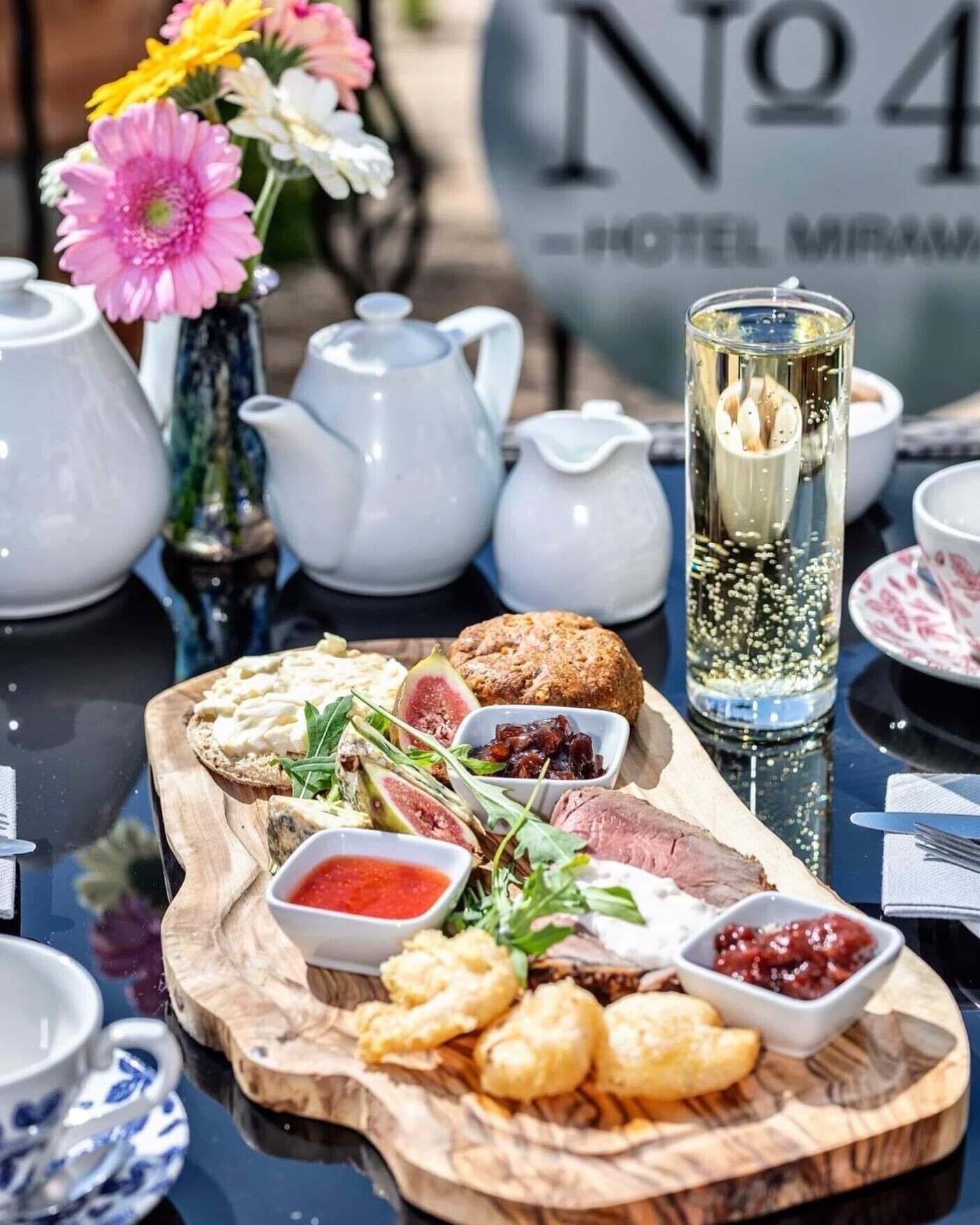 Een gedekte tafel met diverse gerechten, waaronder een vleeswarenplank, brood en een glas champagne.