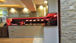Uma cozinha moderna com armários bege, uma ilha central e iluminação vermelha sob os armários.