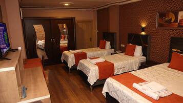 A hotel room with two beds, a desk, a TV, and a mirror.