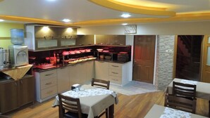 Cozinha compacta com área de refeições, equipada com eletrodomésticos modernos e um dispensador de água.