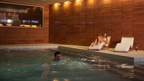 A swimming pool area with a wooden wall, a window, and lounge chairs. - Apartmány Hrádeček (Mlade Buky)