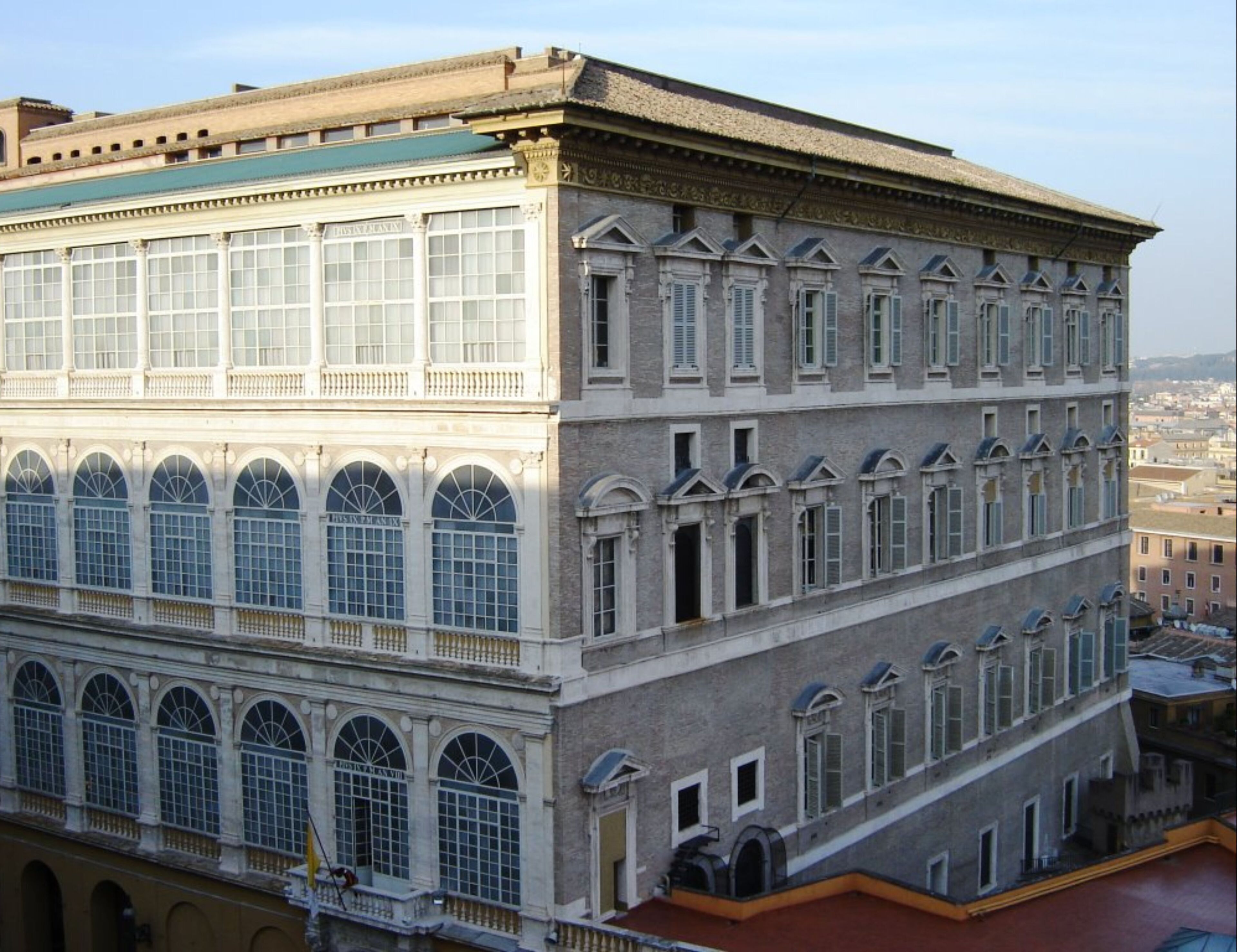 Un edificio de varios pisos con amplias ventanas arqueadas y techo plano.