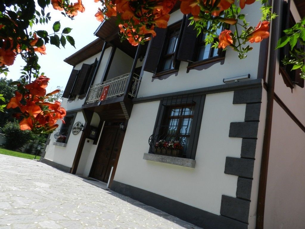 A two-story building with a balcony, a door, and a window with flower boxes.
