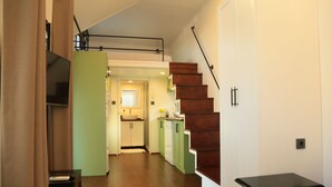 Una cocina moderna con armarios verdes, una escalera de madera y una pequeña mesa.