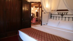 Un dormitorio con cama, un armario de madera y una puerta que da a otra habitación.