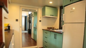 Una cocina funcional con armarios color turquesa, un refrigerador blanco y piso de madera.