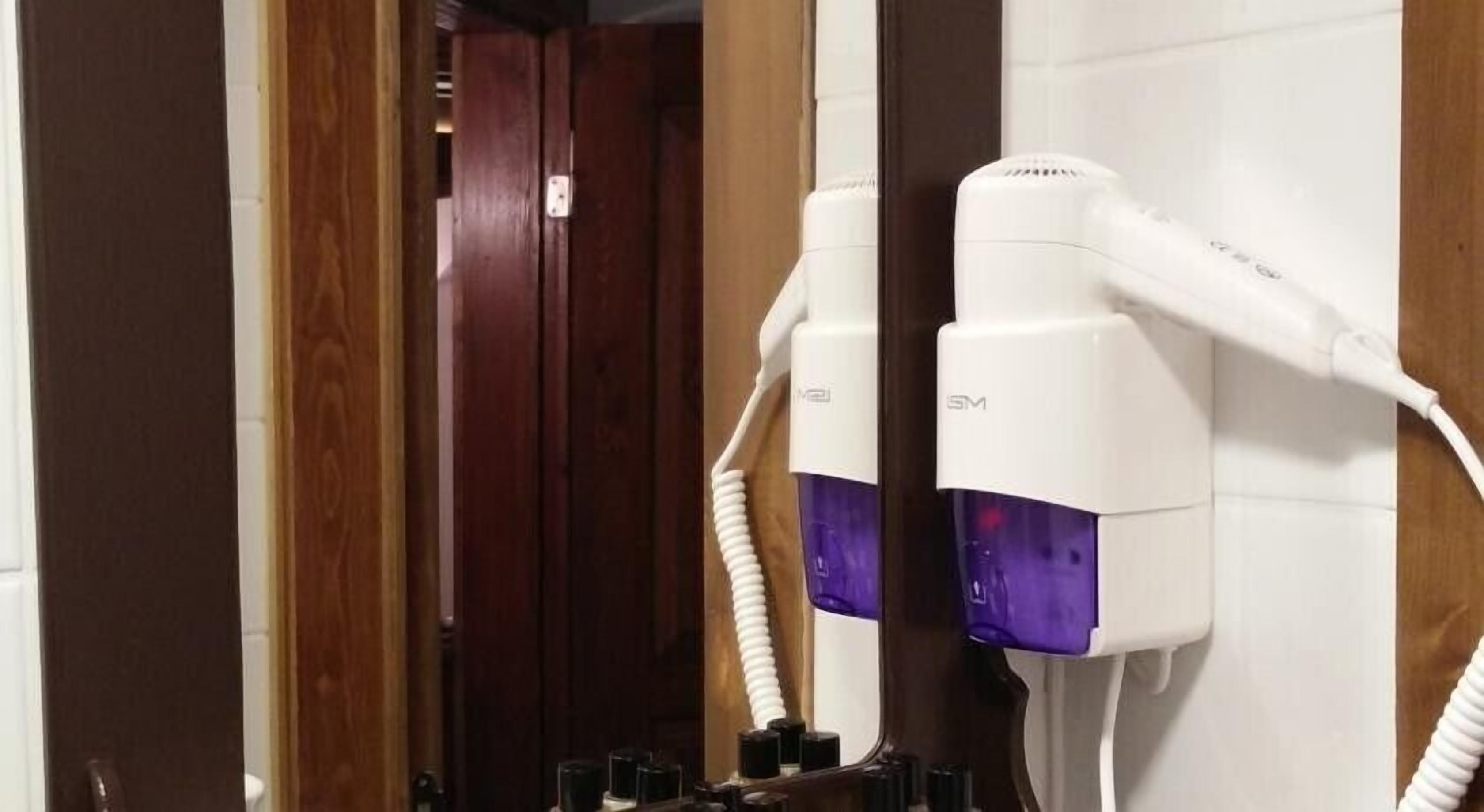 A hair dryer mounted on a wall in a bathroom.