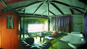 A cabin interior with a glass table, a sofa, a bathtub, and a wooden staircase. - Locanda San Biagio (Misano Adriatico)