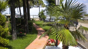 A pathway lined with flowers and trees, leading to a parking area with cars. - Locanda San Biagio (Misano Adriatico)