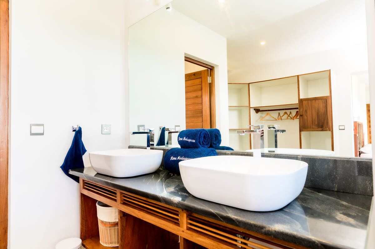 A bathroom with two sinks, a large mirror, and a wooden door.