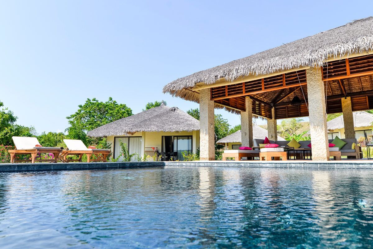 A poolside area with lounge chairs and a covered seating area.