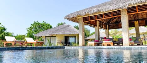 A poolside area with lounge chairs and a covered seating area.