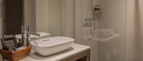 A modern bathroom with a large white sink, a glass shower enclosure, and a wooden vanity.