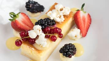 A dessert with strawberries, blackberries, and grapes on a white plate.